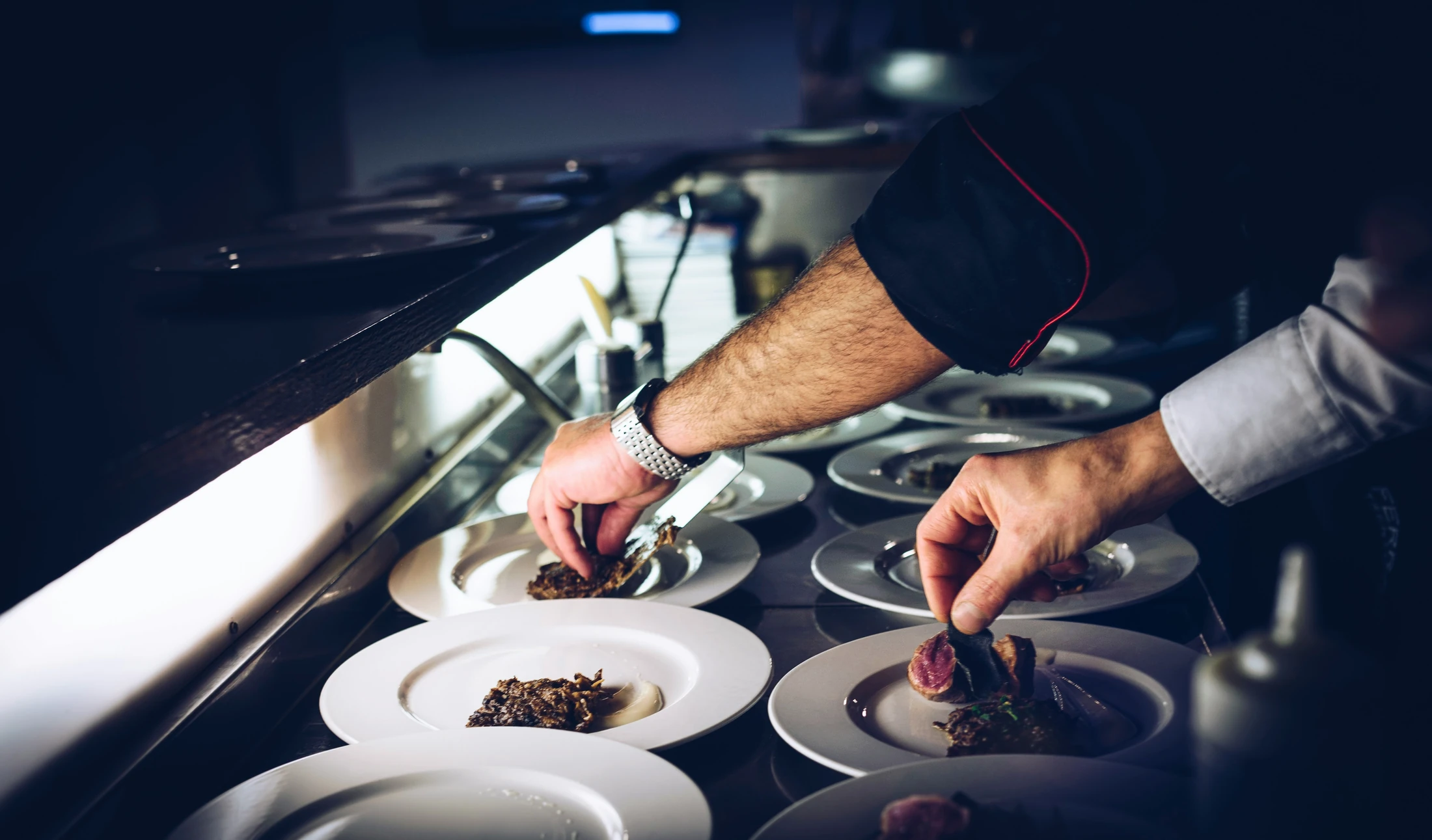 Kitchen staff plating dishes at a restaurant pass